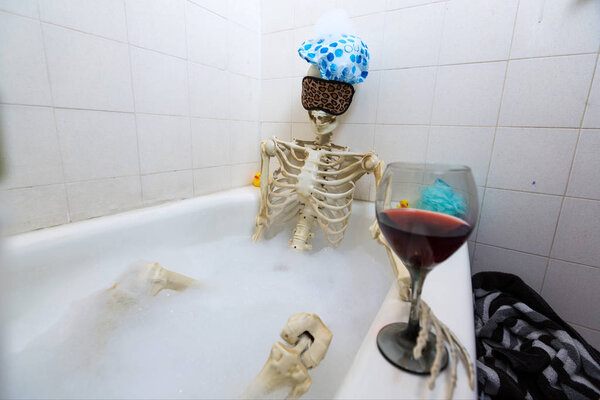 Bony skeleton taking a bubble bath in a grungy off-white dirty tub