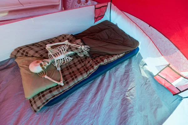 Skeleton relaxing in a tent while camping