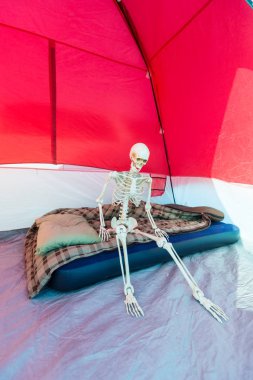 Kamp yaparken çadırda şiltede oturan iskelet