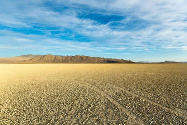 黒い岩の砂漠のプラヤを横切って走るタイヤトラック — ストック写真
