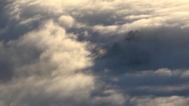  Bulutların yer değiştirmesi zaman aşımına uğruyor. Dağ zirveleri yüzeyi delip geçiyor..