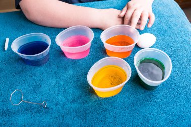 Paskalya yumurtası boyamak için boya tabletlerini bekleyen çocuk.
