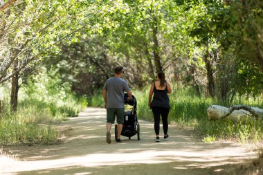 Parkta bebek arabası süren bir çift.