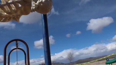 Adult skeleton swinging slow motion low point of view in empty closed park