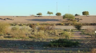 Traffic on a freeway in the desert person walking dog on trail.