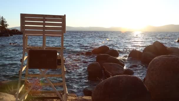 Slow Motion Waves Hitting Rocks Lifeguard Chair Sunset Sun Flared — Wideo stockowe