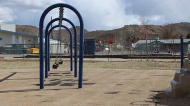 Windy day at an empty playground swings blowing