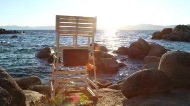 Gün batımında Sand Harbor Gölü Tahoe 'da sahilde kayalara çarpan cankurtaran sandalyesi. 