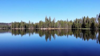  Geriye doğru uç, ağaçların kenarındaki derin mavi dalgalı suyu ortaya çıkar.