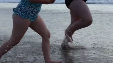  Kumsalda koşan iki kız ağır çekimde su sıçratıyor.