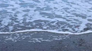 Dalganın kenarındaki okyanus köpüğü kabarcıklar patlıyor ve ağır çekimde yüzüyor. 