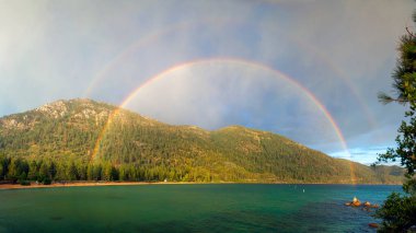 Panorama wide view of colorful double rainbow on Sand Harbor at Lake Tahoe Nevada clipart