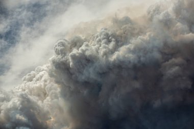 Mavi ve beyaz gökyüzü kabarık kümülonimbus bulutları ve büyük bir yangından çıkan duman