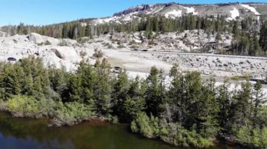 Drone rise up over freeway traffic trees mountains snow on rocks