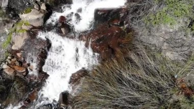 Beyaz su yavaş çekimde çikolata kahverengi kayaların üzerine düşüyor. 