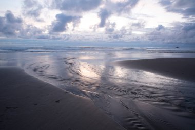 Yokuş yukarı okyanusa akan dere suyu gün batımından sonra bulutların güzel yansımaları.