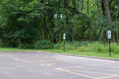 Engelliler için ayrılmış park yeri, engelli işareti ve erişim işaretiyle işaretlenmiş, kamu alanlarında kapsayıcılığı ve erişilebilirliği teşvik eden.