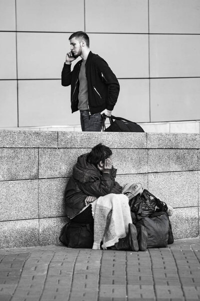poor homeless woman and succesful man near the train station. Black and white images. Central Train Station, 15.10.2018  Ukraine, Kiev.