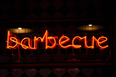 Parlayan Neon kırmızı işareti Barbekü ve siyah arka planda bulanık ışıklar.