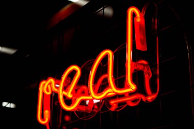Siyah arka planda parlayan Neon kırmızı işareti gerçek ve bulanık ışıklar.