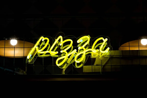 Świecący Neon żółty znak Pizza i niewyraźne światła na czarnym tle — Zdjęcie stockowe