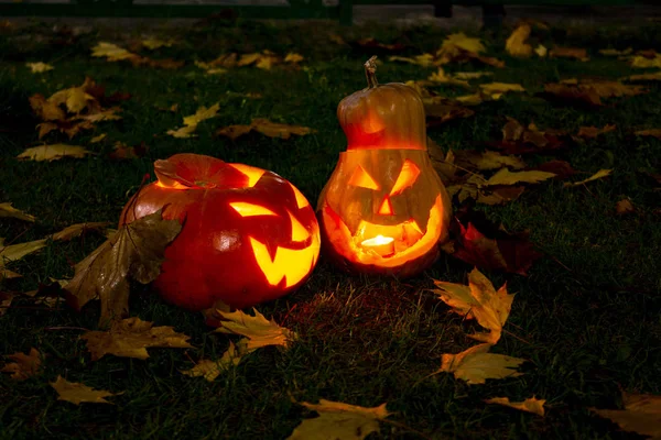 Halloween pumpkins with carved demonic faces and candles inside.