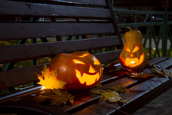 Halloween pumpkins with carved demonic faces and candles inside.