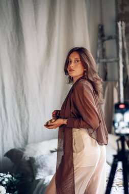 Güzel, genç bir kadın, güzel bir iç mekanı olan eski bir odada şarkı kasesiyle poz veriyor. Arka planda çatı katı tarzında tuğla bir duvar var. Yoga pratiği, ses iyileştirme, ezoterizm..