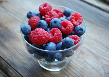 bir cam bowl.raspberries, blueberries.wooden kahverengi arka plan parlak, Olgun çilek