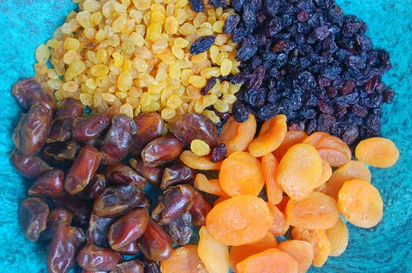 dry fruits, raisins light and dark, dried apricots and dates.on a blue background