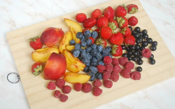 木製の茶色の背景にベリーや果物 イチゴ ラズベリー ブルーベリー カラントと桃 — ストック写真