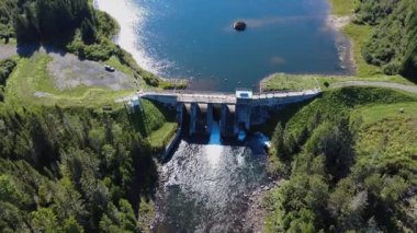Işıl ışıl Lac Mitis 'in hava manzarası ve dağlık ormanın ortasında bir arabanın park ettiği eski hidroelektrik barajı. Lac-des-eaux-mortes, Quebec, Kanada, 2025.