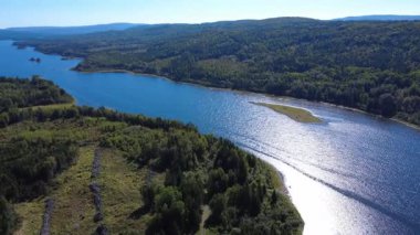 Ormanla çevrili Mitis Gölü 'nün panoramik hava manzarası. Bu göl, su seviyesini yükselten bir hidroelektrik barajının inşası nedeniyle üç eski gölün birleşmesinin sonucudur. Quebec, Kanada, 2025.