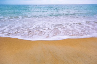 Kumlu sahilde yumuşak bir mavi okyanus dalgası. Arkaplan.