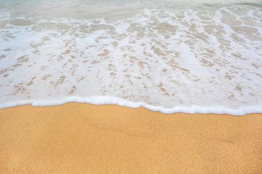 Kumlu sahilde yumuşak bir mavi okyanus dalgası. Arkaplan.