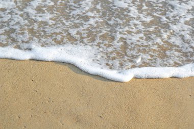 Kumlu sahilde yumuşak bir mavi okyanus dalgası. Arkaplan.