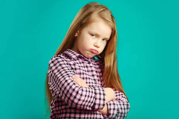 Fille offensée avec les bras croisés au sein, visage gonflé de colère et d'insatisfaction, exprime son mécontentement, portrait de l'enfant de mauvaise humeur sur bleu isolé . — Photo