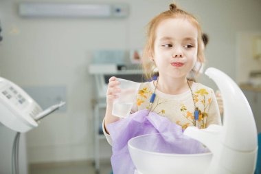 Child rinses out mouth and sits in dentist chair clipart