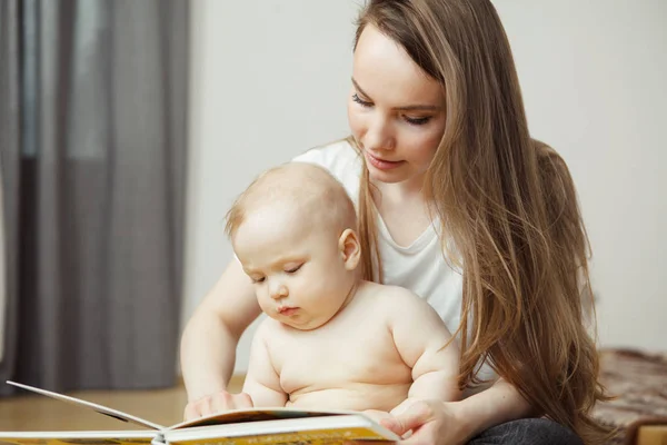 Мать читает маленькому младенцу красочную книгу со сказками . — стоковое фото
