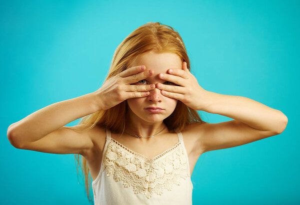 Рыжая девушка закрыла глаза руками, подглядывая сквозь пальцы.
.