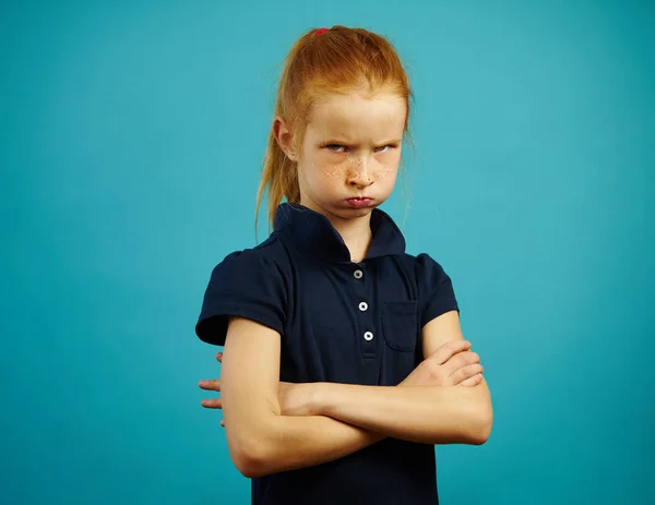 Retrato de menina ofendida com a boca inflada e braços cruzados, expressa insatisfação ou ressentimento, demonstra caráter difícil, fica em fundo azul isolado . — Fotografia de Stock