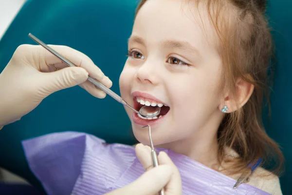 Child lies in dentist chair and doctor does checkup — Stock Photo, Image