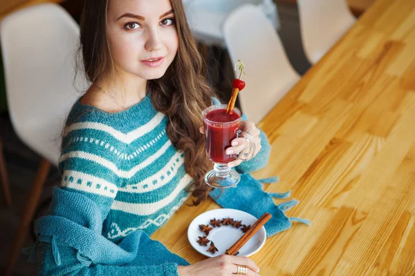 Brown-haired woman drinking smoothie with cinnamon alone in cafe