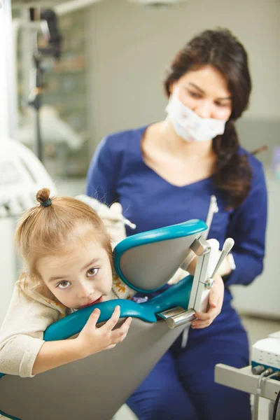 Niño pequeño con miedo a los procedimientos en el consultorio del dentista — Foto de Stock