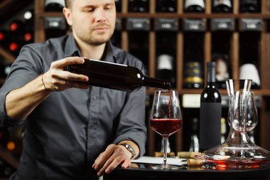 Şarap garsonu bardaktan kırmızı şarap dolduruyor.