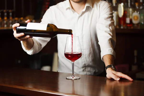 Чоловічий сомельє, що поливає червоне вино в довгоногі келихи винограду . — стокове фото