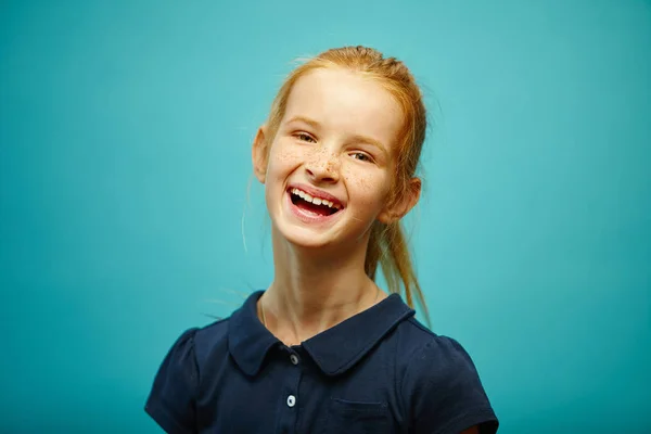 Rindo menina ruiva criança, retrato em azul isolado — Fotografia de Stock