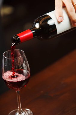 Garson şarap kadehine kırmızı şarap dolduruyor. Sommelier alkollü içecek doldurur.