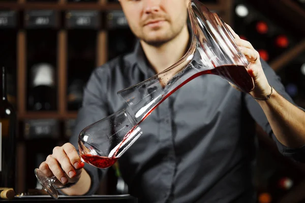 Sommelier häller vin i glas från att blanda skål. Manlig servitör — Stockfoto