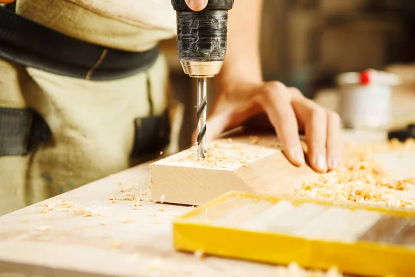 Wood boring drill in hand drilling hole in wooden bar — Stock Photo, Image